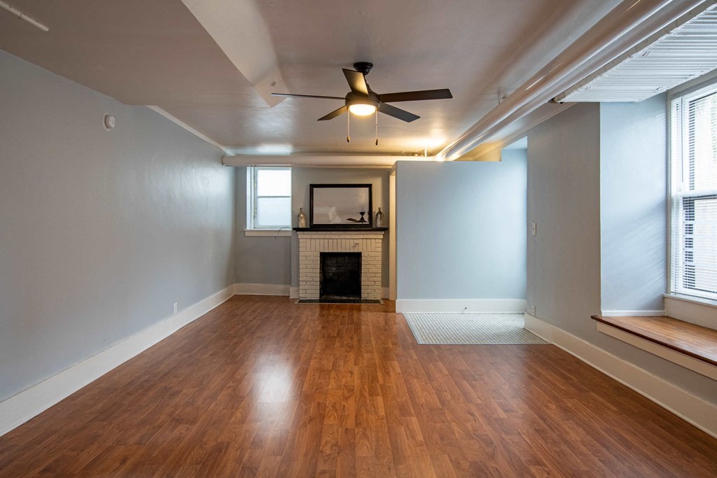 an empty living room with a fireplace and a ceiling fan