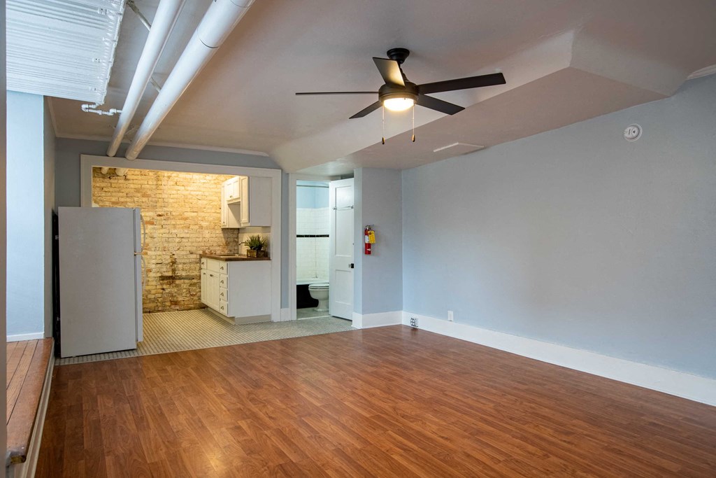 an empty living room with wood floors and a ceiling fan