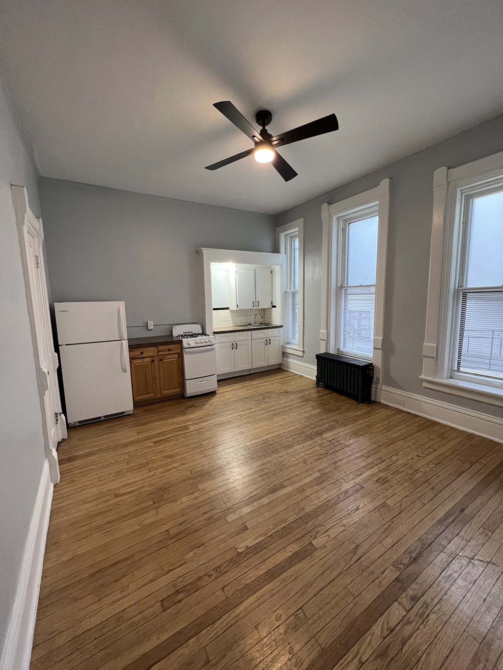 an empty living room with a ceiling fan and a kitchen