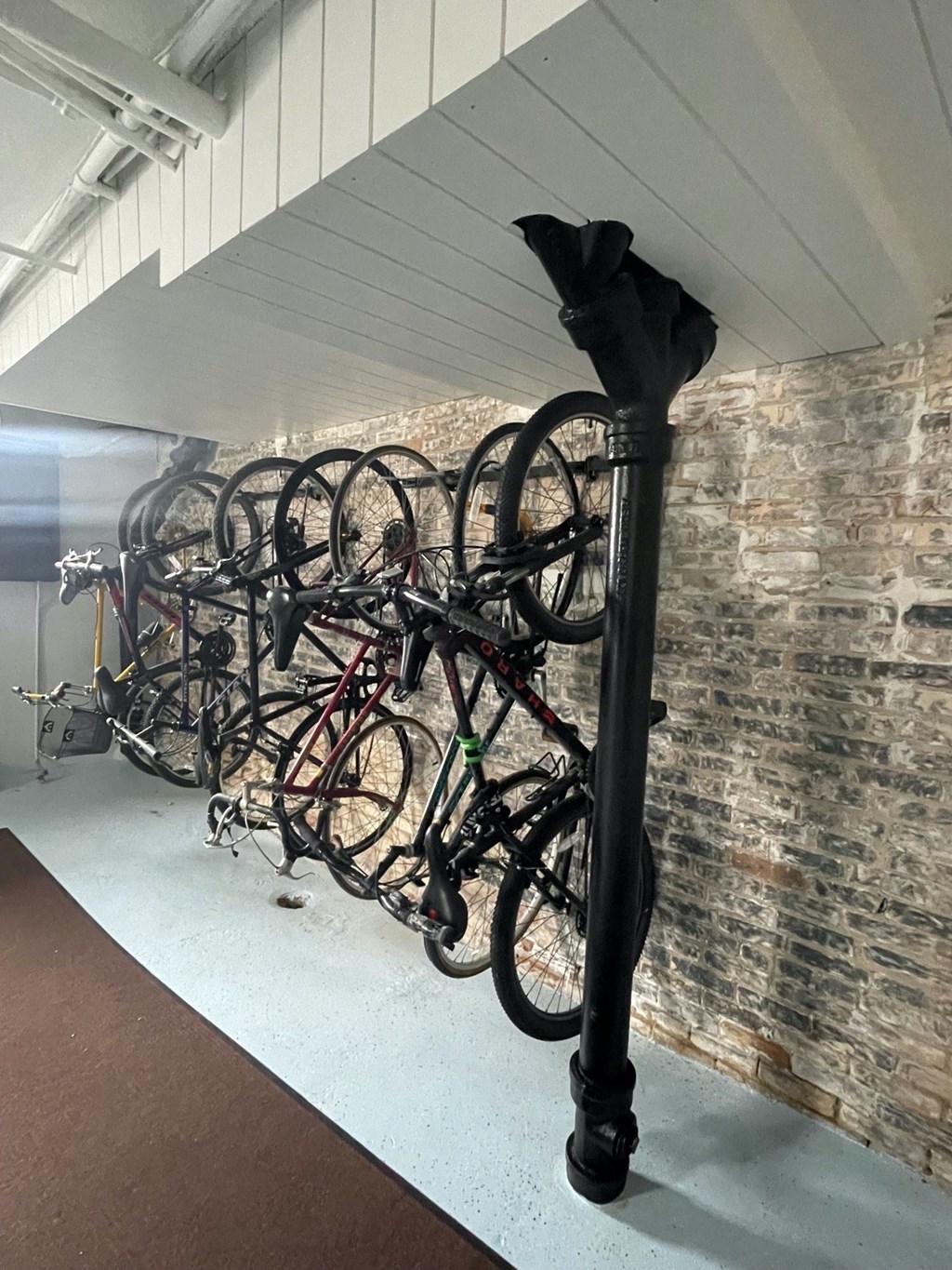 a row of bikes on a pole in front of a brick wall