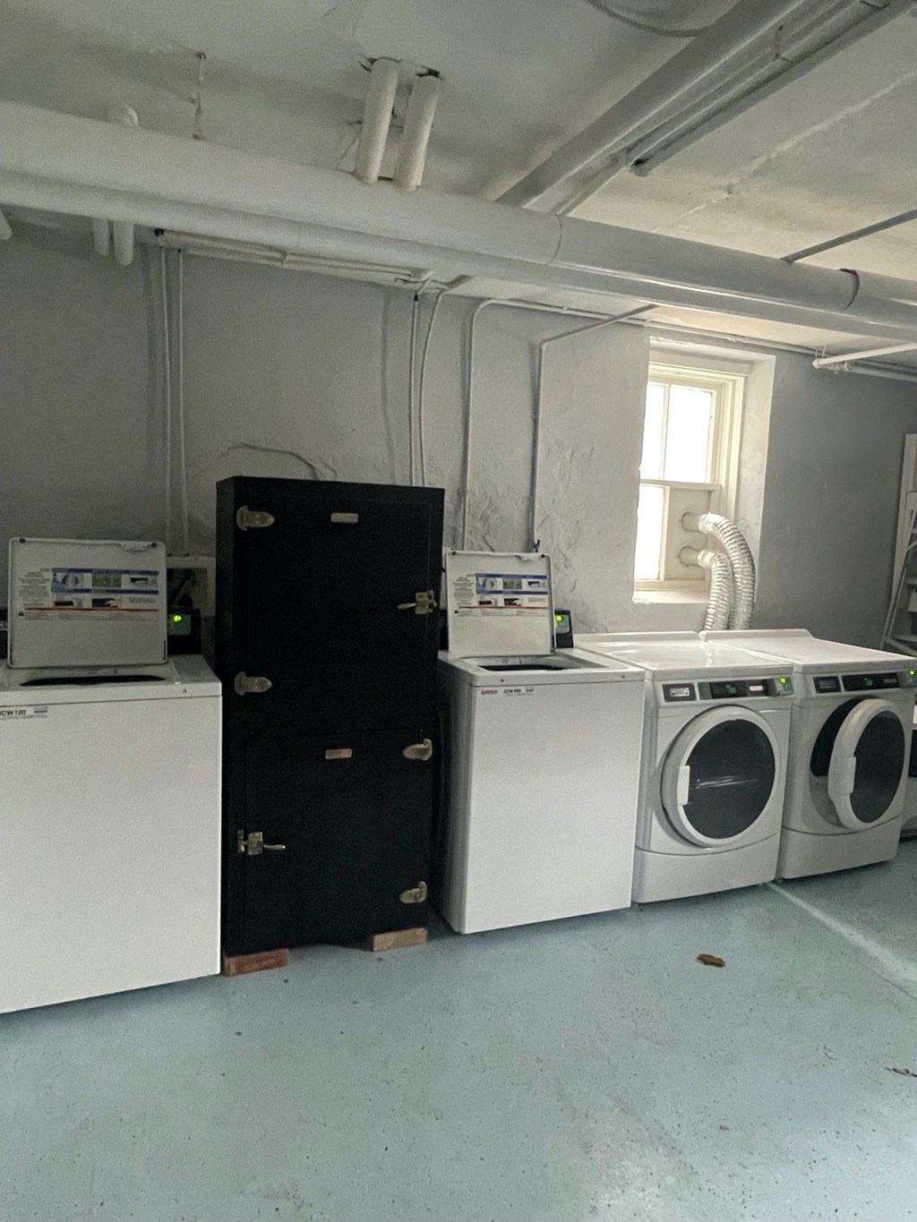 a laundry room with three washing machines and a black door