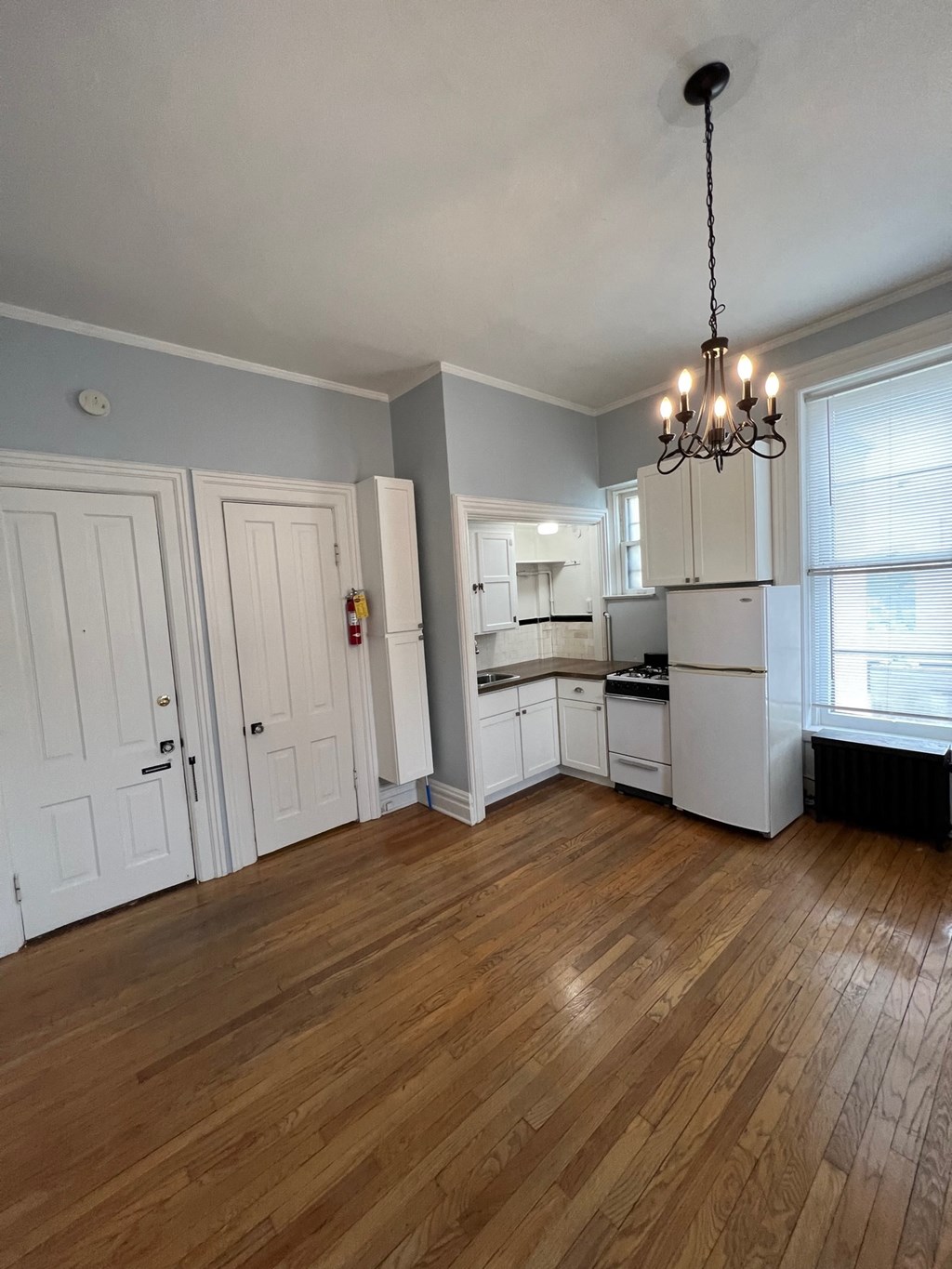 an empty living room with a kitchen and a chandelier