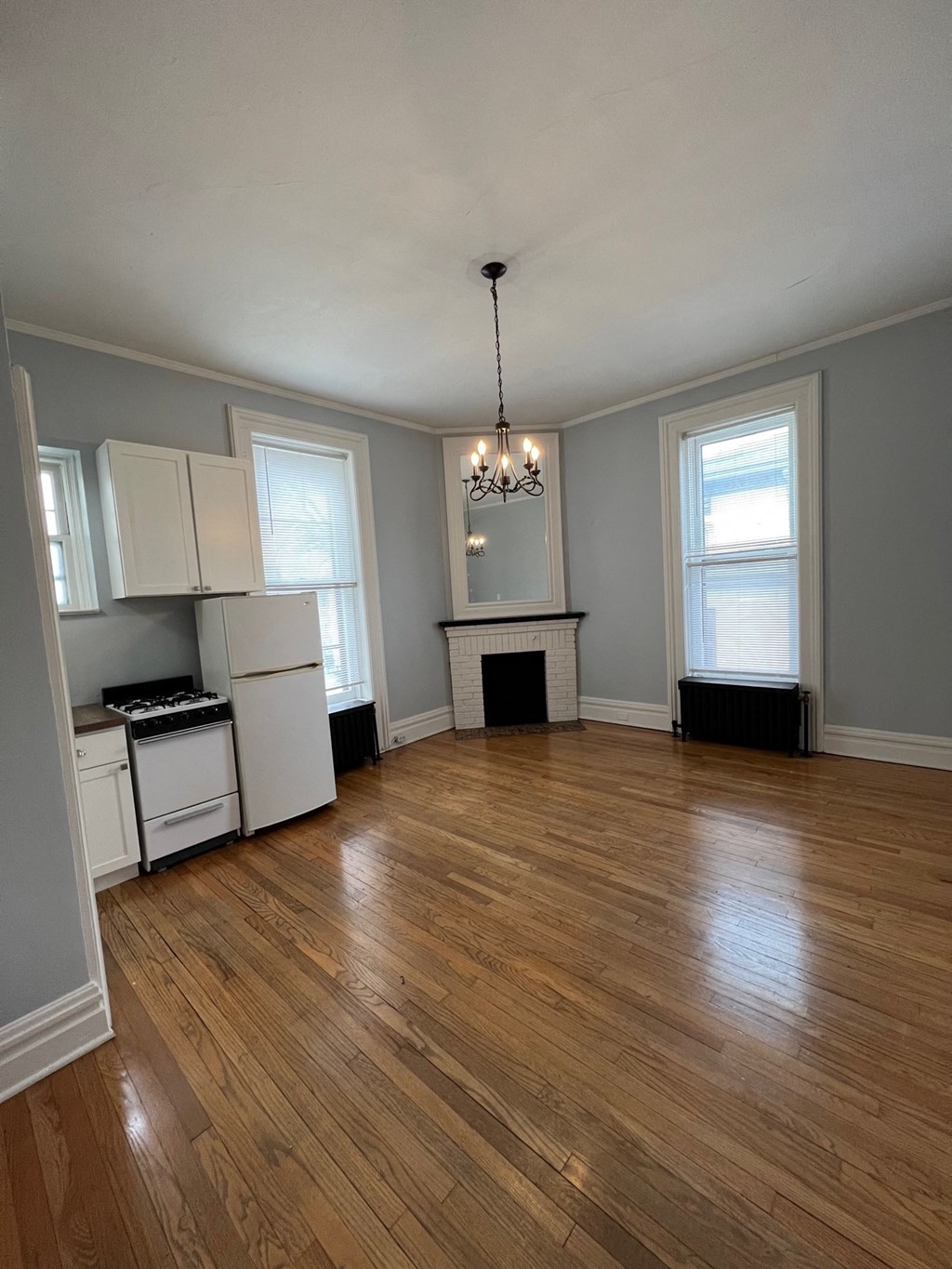 an empty living room with a kitchen and a hard wood floor