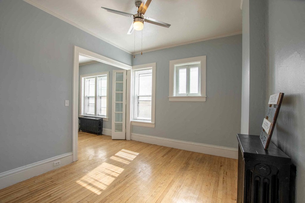 an empty living room with a ceiling fan and windows
