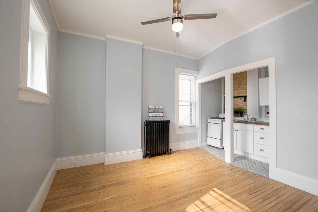 an empty living room with blue walls and a ceiling fan