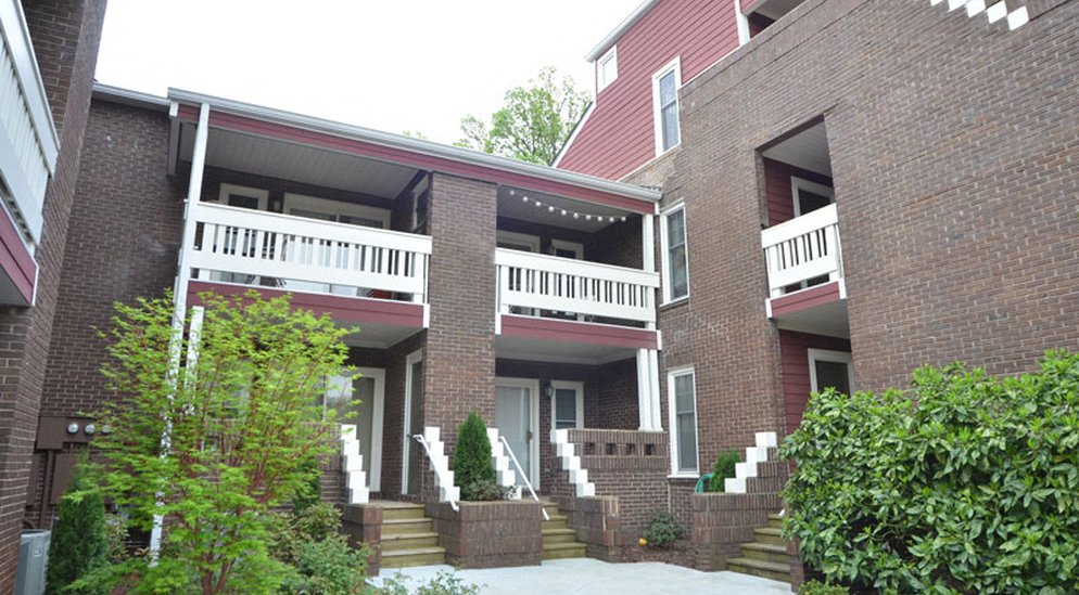 a brick house with a porch and a white balcony