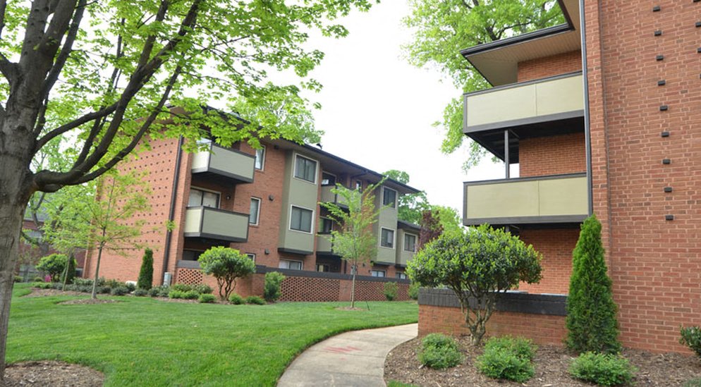 an apartment building with a green lawn and a sidewalk