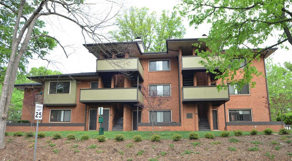 a large brick apartment building with green balconies
