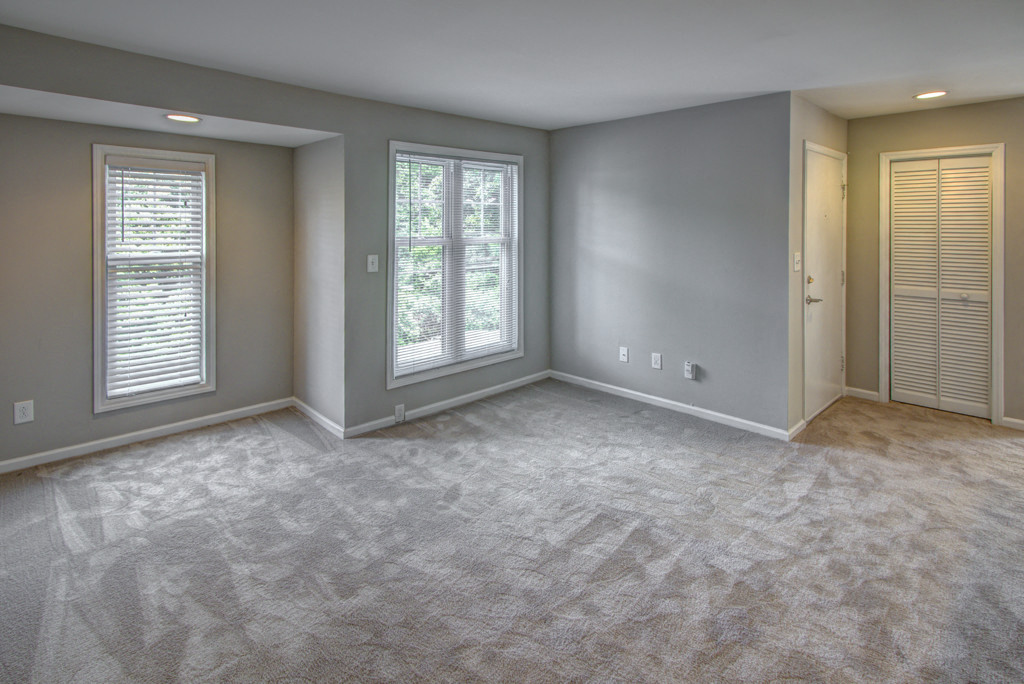 an empty living room with two windows and a door