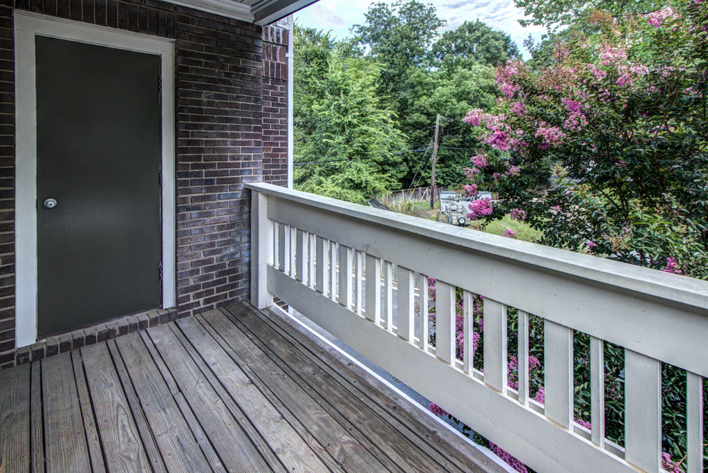 the view from the balcony of a brick house with a wooden deck and a door