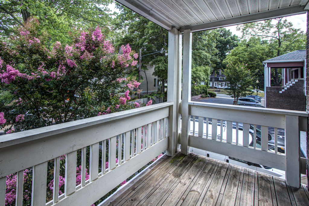 a porch with a view of a flowering tree and a street