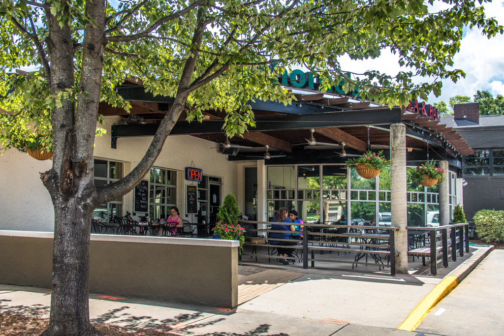 the outside of a restaurant with people sitting at tables