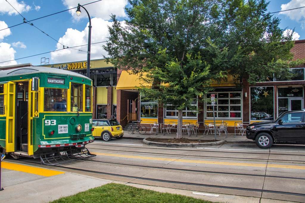 a green and yellow streetcar traveling down a city street