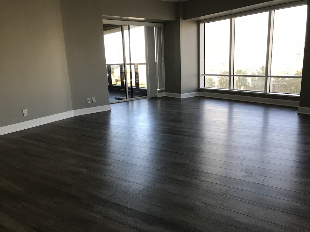 an empty living room with wood floors and large windows