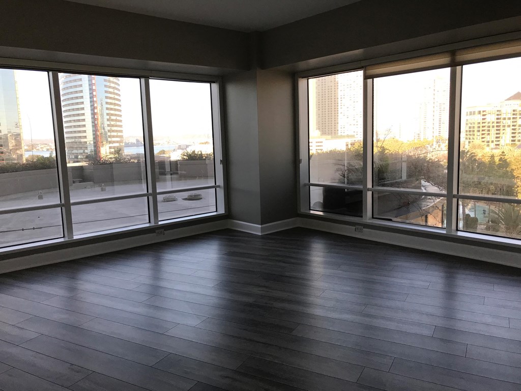 an empty living room with wood floors and large windows