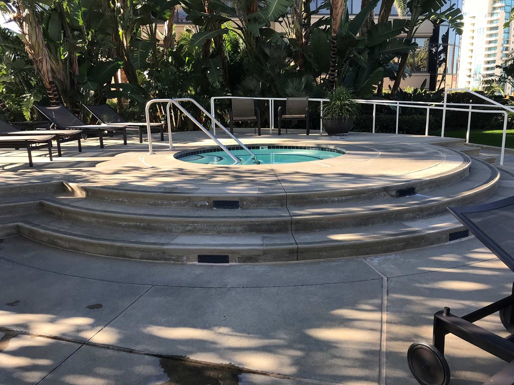 a hot tub in a park with benches and palm trees