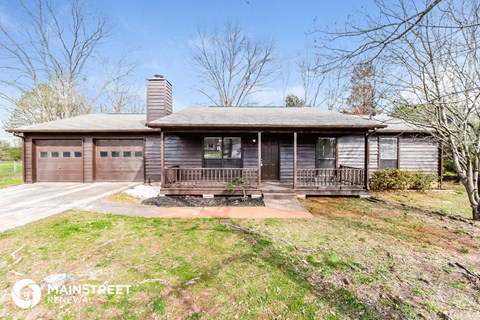 a brown house with a porch and a wooden deck