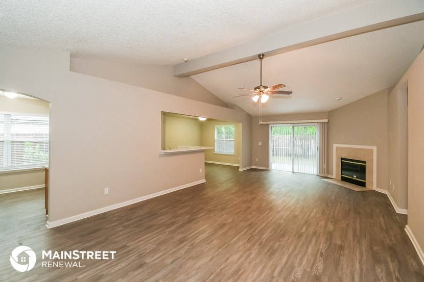the living room and dining room with wood flooring and a ceiling fan