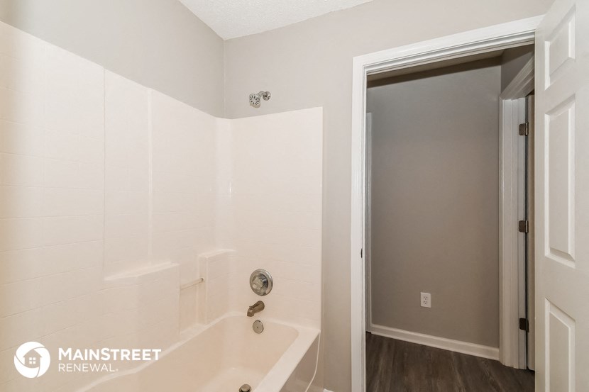 a bathroom with a tub and a shower and a door to a closet