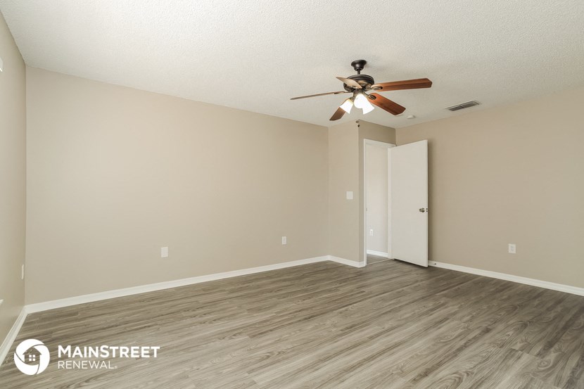the spacious living room with wood flooring and a ceiling fan