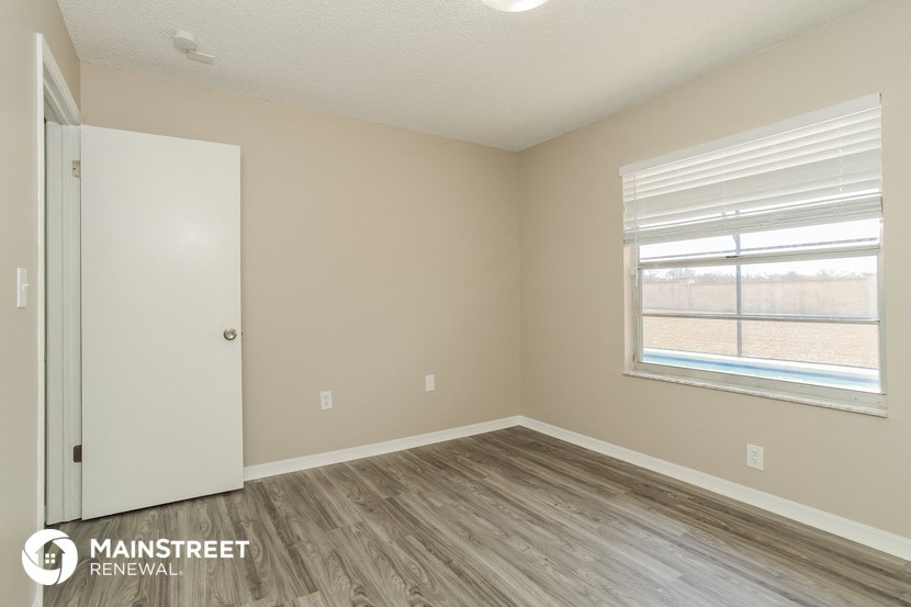 the interior of an empty room with wood flooring and a window