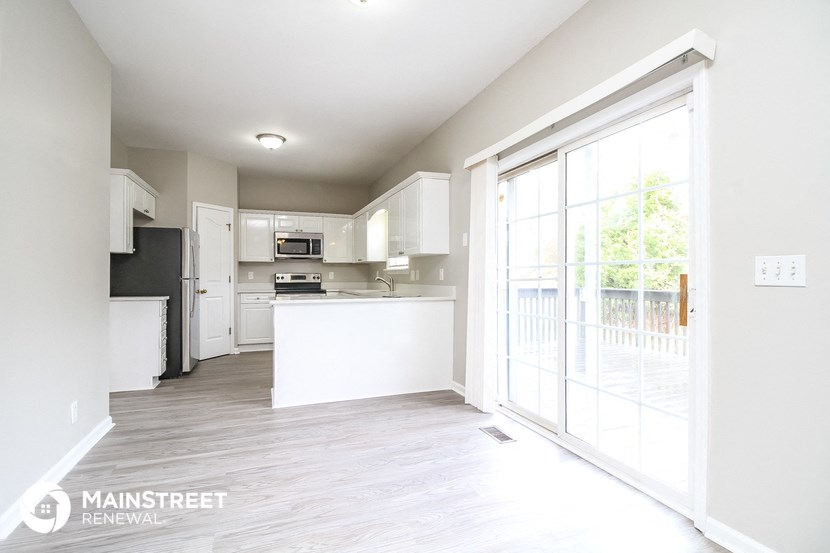 an open kitchen and living room with a door to a balcony