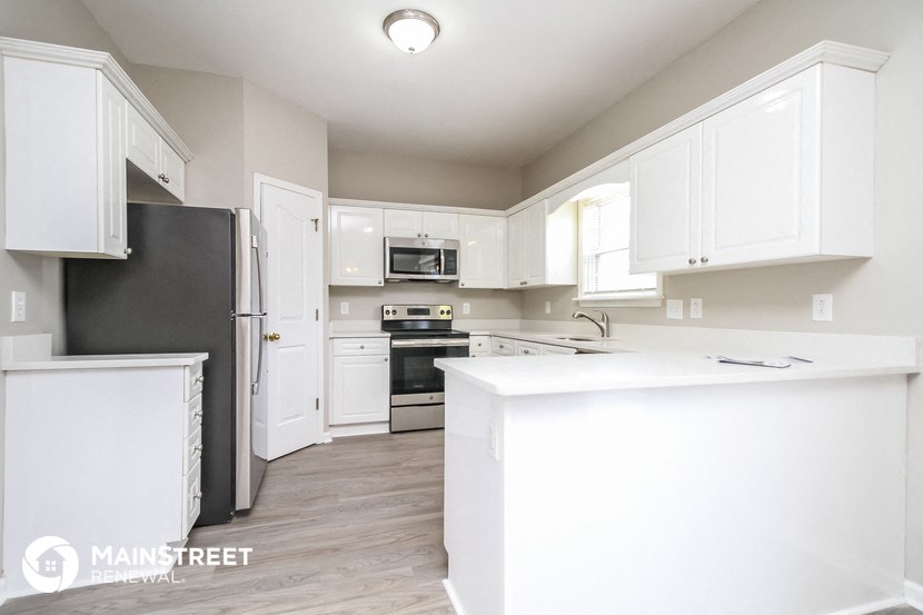 a white kitchen with white cabinets and stainless steel appliances