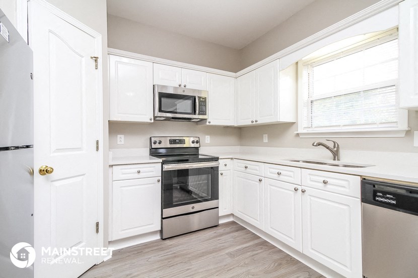 a white kitchen with stainless steel appliances and white cabinets