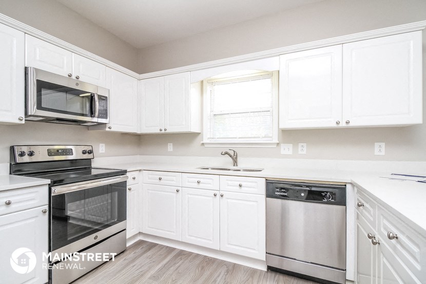a white kitchen with stainless steel appliances and white cabinets