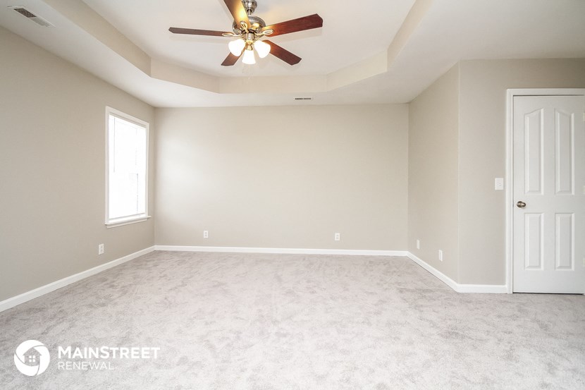 the master bedroom with carpet and a ceiling fan