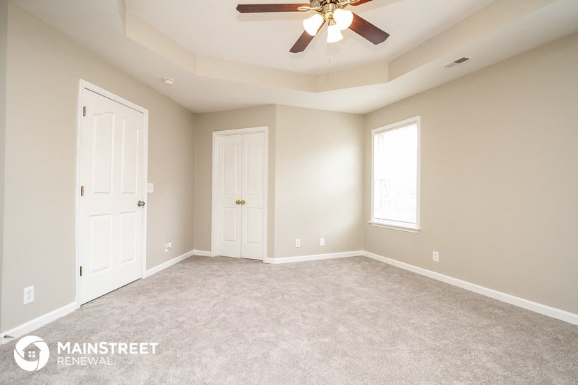 an empty room with a ceiling fan and two doors