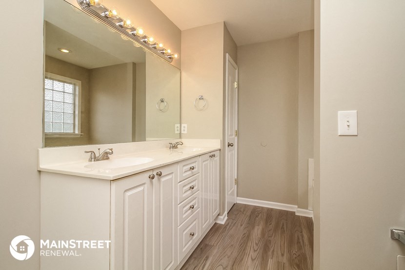 a bathroom with white cabinets and a sink and a mirror