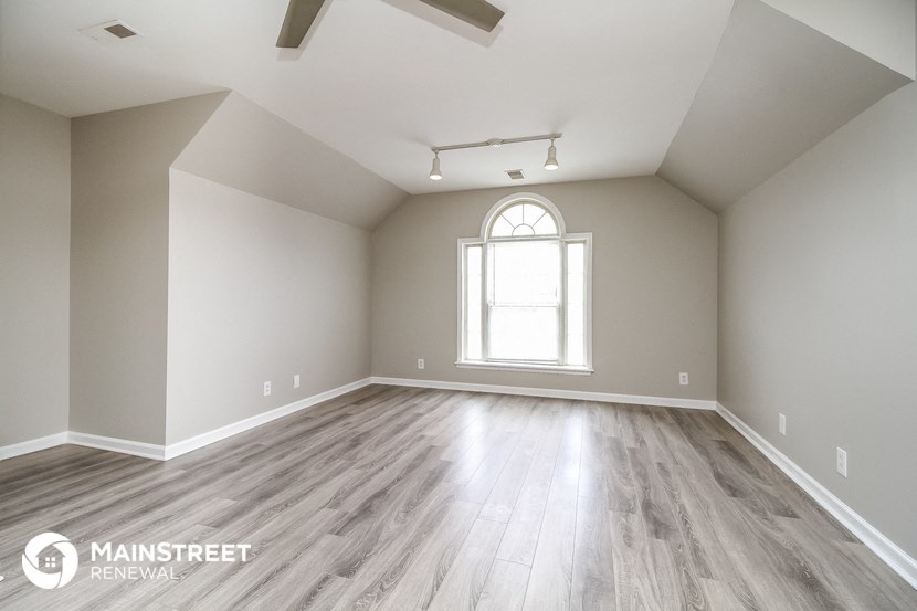 the spacious living room with wood flooring and an arched window