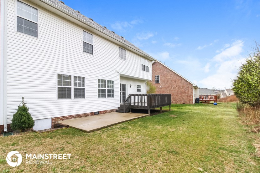 the back porch of a white house with a wooden deck