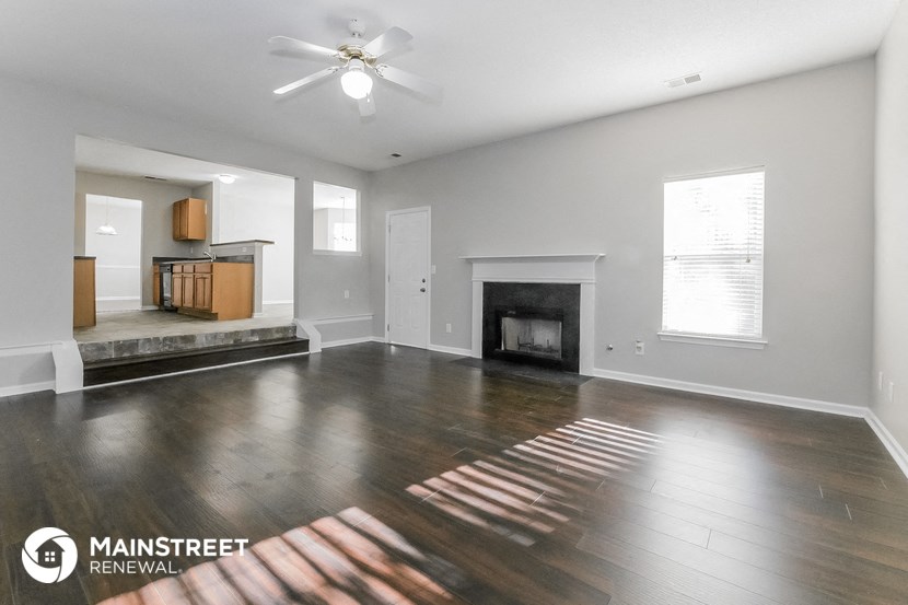 an empty living room with wood flooring and a fireplace