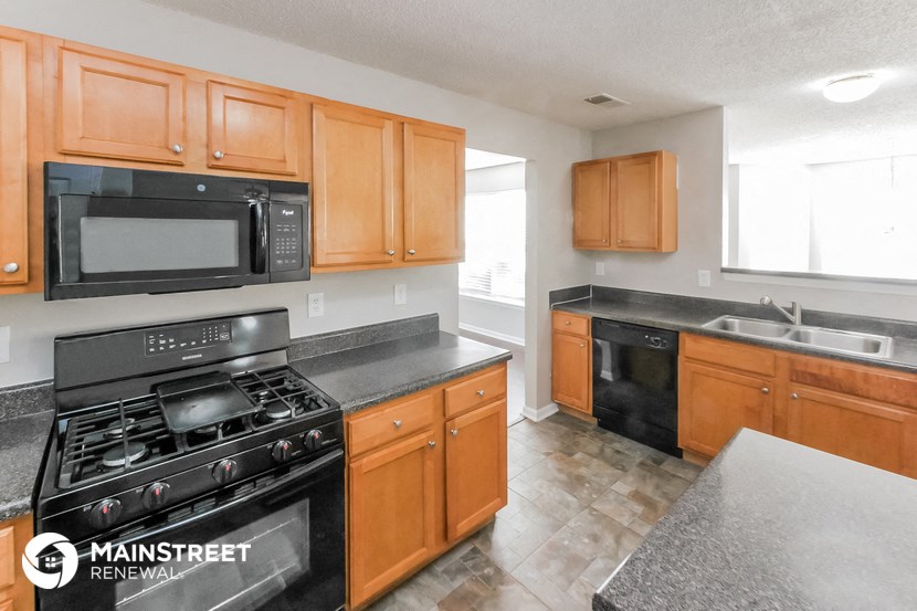 a kitchen with wood cabinets and black appliances and black counter tops