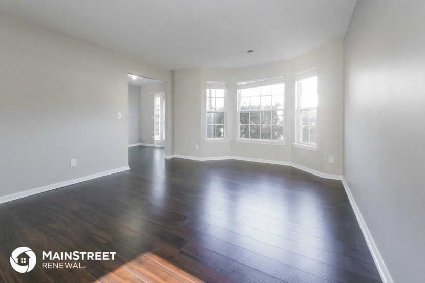 an empty living room with wood floors and windows