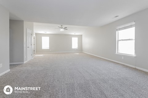 the spacious living room with white walls and carpet