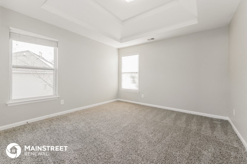 the spacious living room with carpeting and two windows