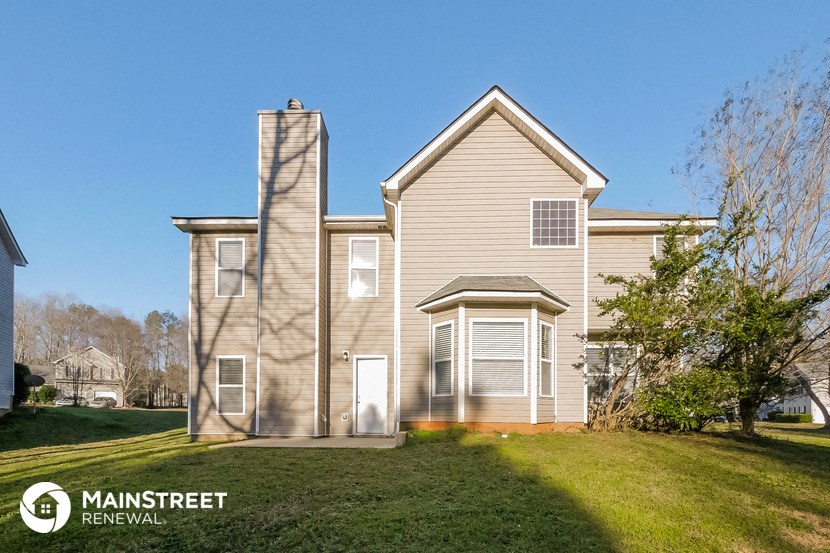 a side view of a house with a lawn and a tree