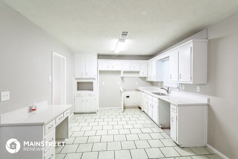 a large white kitchen with white cabinets and white tiled floors