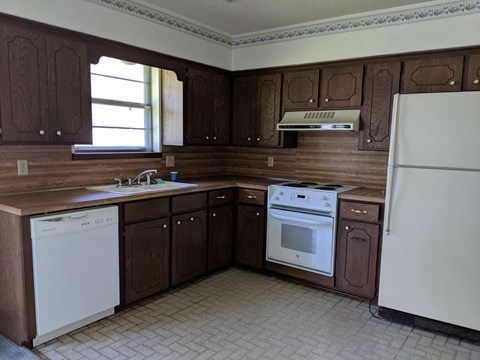 A kitchen with brown cabinets and white appliances.