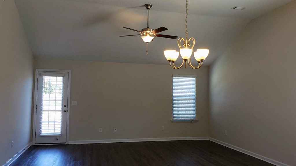 an empty living room with a ceiling fan and a door