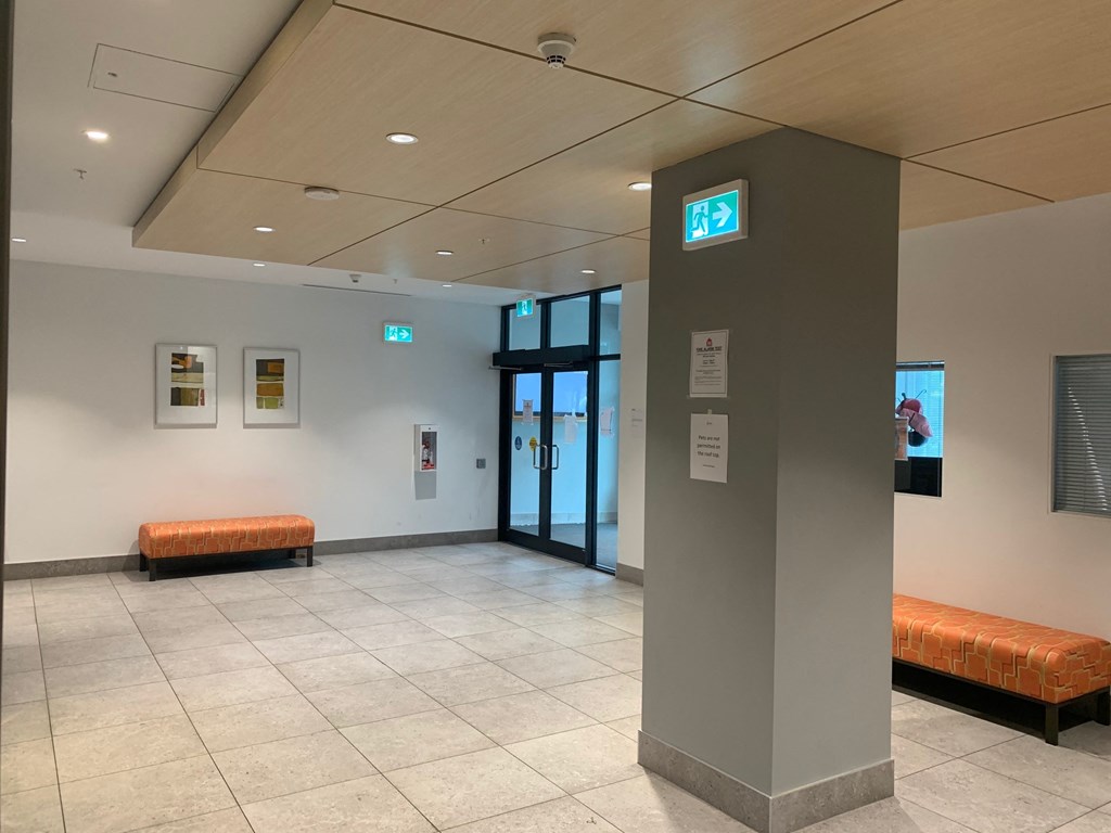 a lobby with orange benches and a pillar and a door