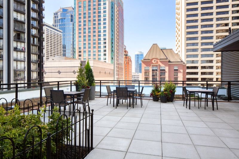 a rooftop terrace with tables and chairs and a view of the city