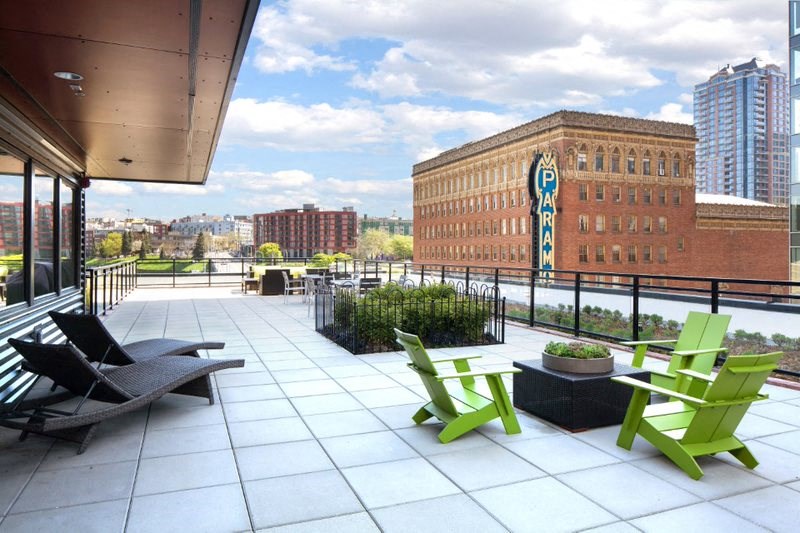 a roof terrace with green chairs and a view of the city