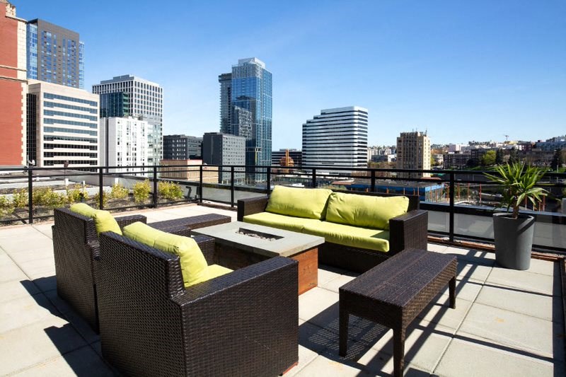 a rooftop patio with furniture and a city in the background