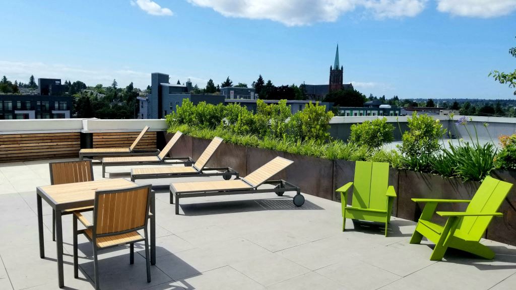 a rooftop patio with chairs and tables and a city in the background