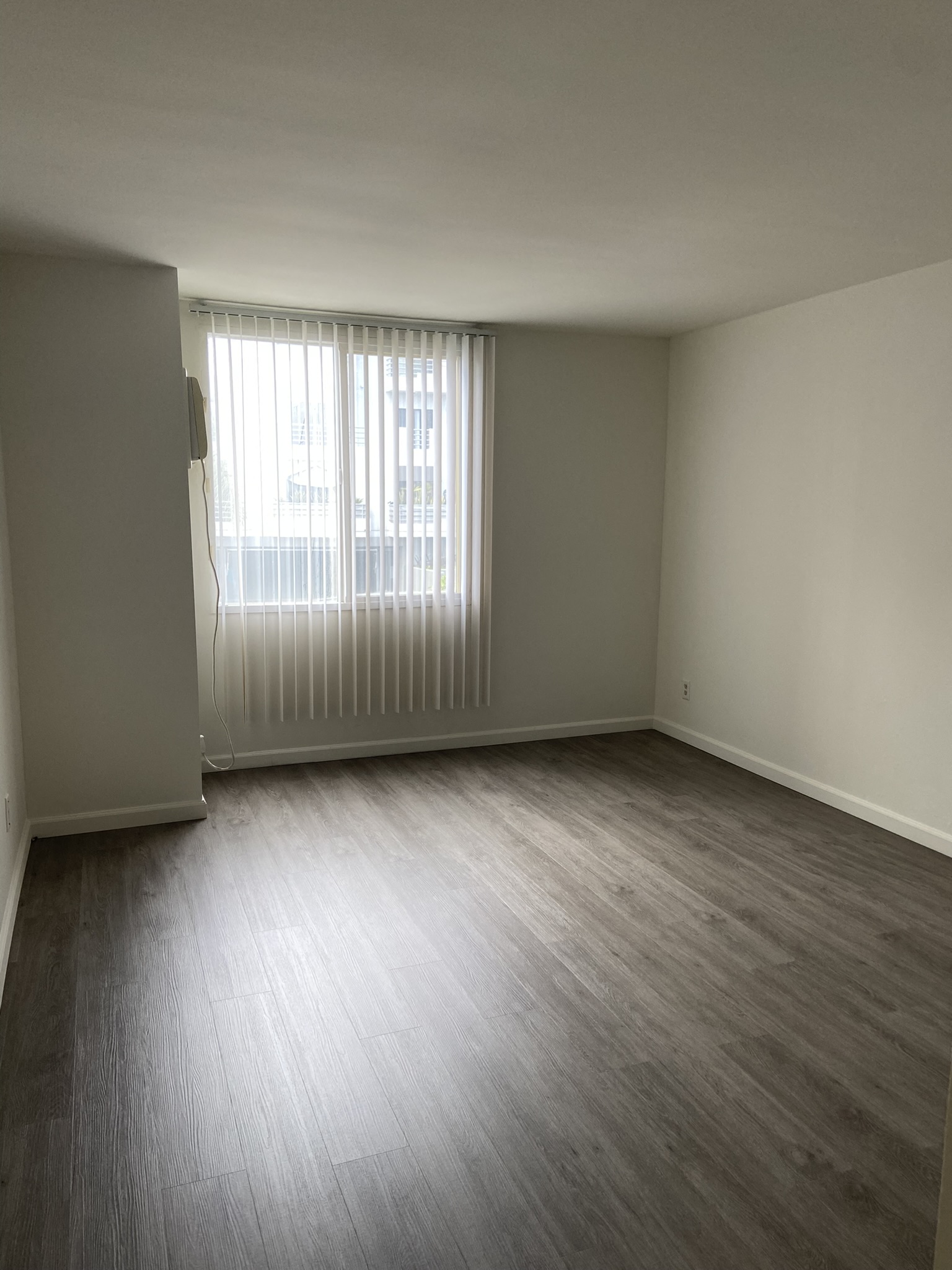 an empty living room with wood floors and a window