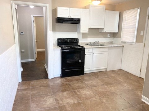 A kitchen with a black oven and white cabinets.